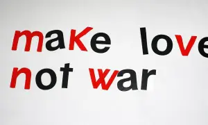 Napis "make love not war" w stylu pacyfista. Czerwone litery podkreślają przesłanie pokoju.