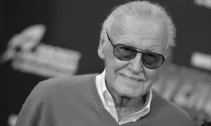 Uśmiechnięty Stan Lee Marvel w okularach przeciwsłonecznych, z siwymi włosami i charakterystycznymi wąsami.
