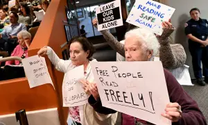 Protest przeciwko cenzurze w bibliotece. Ludzie trzymają transparenty: "Wolni ludzie czytają swobodnie", "Zostawcie nasze dzieci w spokoju", "Uczyńmy czytanie znów bezpiecznym".