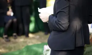 Kobieta w czerni trzyma kartkę, być może czyta panegiryk. Co to jest? To mowa pochwalna, często wygłaszana na pogrzebie.