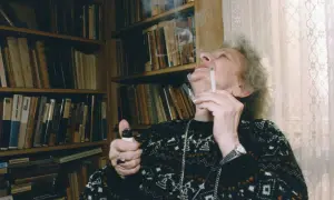 Wisława Szymborska, zapalając papierosa, otoczona książkami. Ciekawe, o czym myślała?
