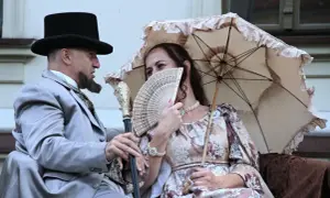 Para jak z obrazu, lalka bohaterowie w strojach z epoki, mężczyzna z wąsem i cylinder, kobieta z wachlarzem i parasolką.