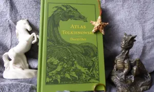Zielona okładka "Atlasu Tolkienowskiego" z wizerunkiem smoka, obok figurka konia i smoka, oraz pierścień. To wszystko, co napisał Tolkien, w jednym miejscu.