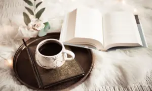 Kawa i otwarta księga, pełna mądrości i cytatów z biblii, na miękkim kocu.