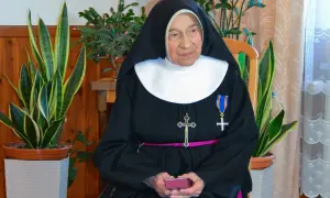 Siostra Antygony, w habicie i z krzyżem, siedzi wśród roślin. Może to być rozwiązanie krzyżówki z jej udziałem.