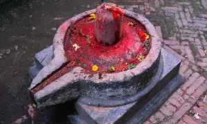 Kamienna podstawa z rynienką, na niej czerwony, ozdobiony kwiatami lingam, symbolizujący boga Śiwę.