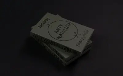 Stos książek z napisem "ANTYNATALIZM" i symbolem nożyczek.