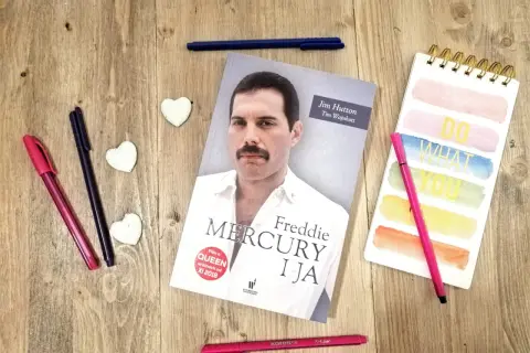 Książka "Freddie Mercury i ja" leży obok kolorowych pisaków i notatnika.