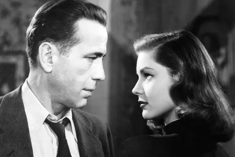 Para z filmu noir patrzy na siebie w zbliżeniu. Mężczyzna w garniturze, kobieta w czarnej sukni.