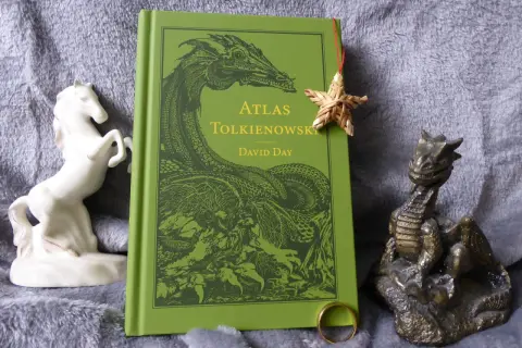 Zielona okładka "Atlasu Tolkienowskiego" z wizerunkiem smoka, obok figurka konia i smoka, oraz pierścień. To wszystko, co napisał Tolkien, w jednym miejscu.