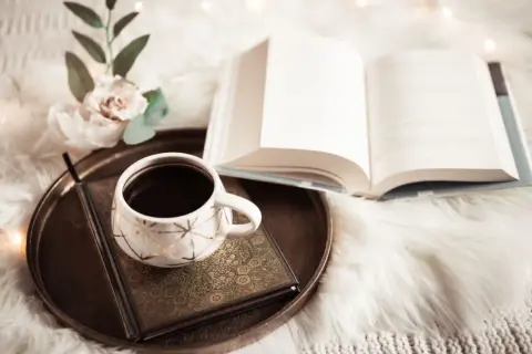 Kawa i otwarta księga, pełna mądrości i cytatów z biblii, na miękkim kocu.