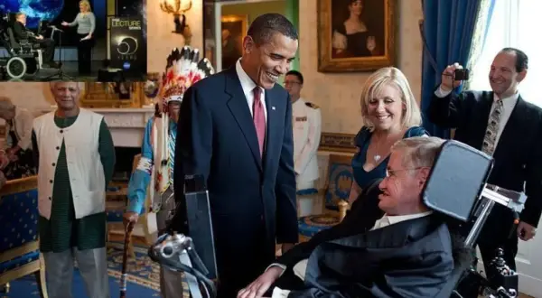 Barack Obama wita Stephena Hawkinga, naukowca na wózku, w Białym Domu. W tle widać innych gości i obrazy.