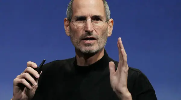 Steve Jobs, w okularach i czarnym golfie, trzyma w dłoni mały przedmiot. Ciekawe fakty o jego życiu i karierze.