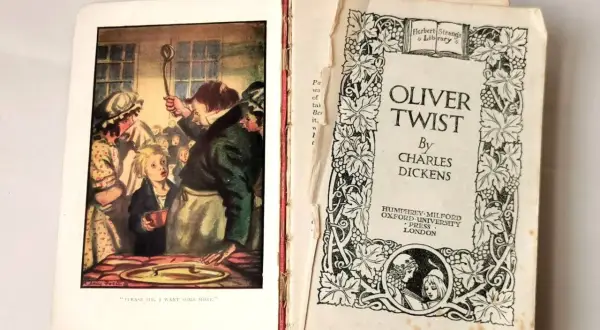 Otwarta książka z ilustracją Olivera Twista proszącego o dokładkę i stroną tytułową.