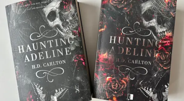 Dwie książki "Haunting Adeline" i "Hunting Adeline" H.D. Carlton. Mroczne okładki z czaszką, różami i pajęczyną.
