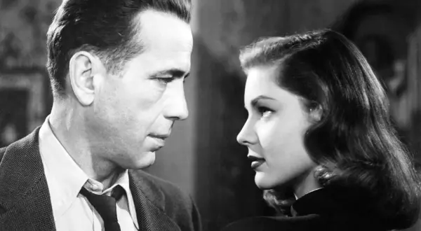 Para z filmu noir patrzy na siebie w zbliżeniu. Mężczyzna w garniturze, kobieta w czarnej sukni.