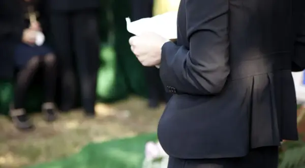 Kobieta w czerni trzyma kartkę, być może czyta panegiryk. Co to jest? To mowa pochwalna, często wygłaszana na pogrzebie.
