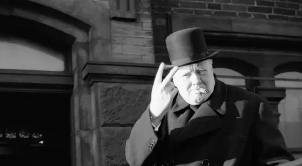 Winston Churchill z cygarem i kapeluszem, pokazujący znak zwycięstwa. Ciekawostki o nim często dotyczą jego charyzmy.