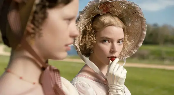 Emma, z powieści Jane Austen, w białej rękawiczce wkłada truskawkę do ust.