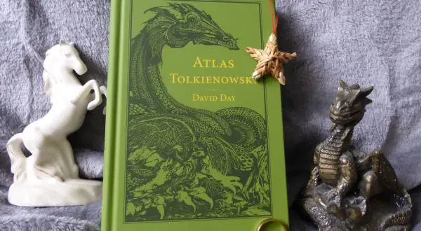 Zielona okładka "Atlasu Tolkienowskiego" z wizerunkiem smoka, obok figurka konia i smoka, oraz pierścień. To wszystko, co napisał Tolkien, w jednym miejscu.