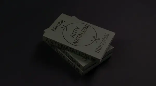 Stos książek z napisem "ANTYNATALIZM" i symbolem nożyczek.