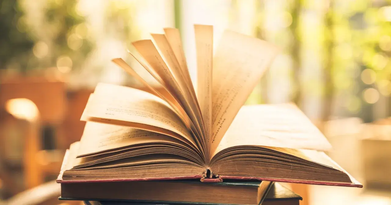 Otwarta księga, której strony wirują na wietrze, symbolizując mądrość i cnoty kardynalne.