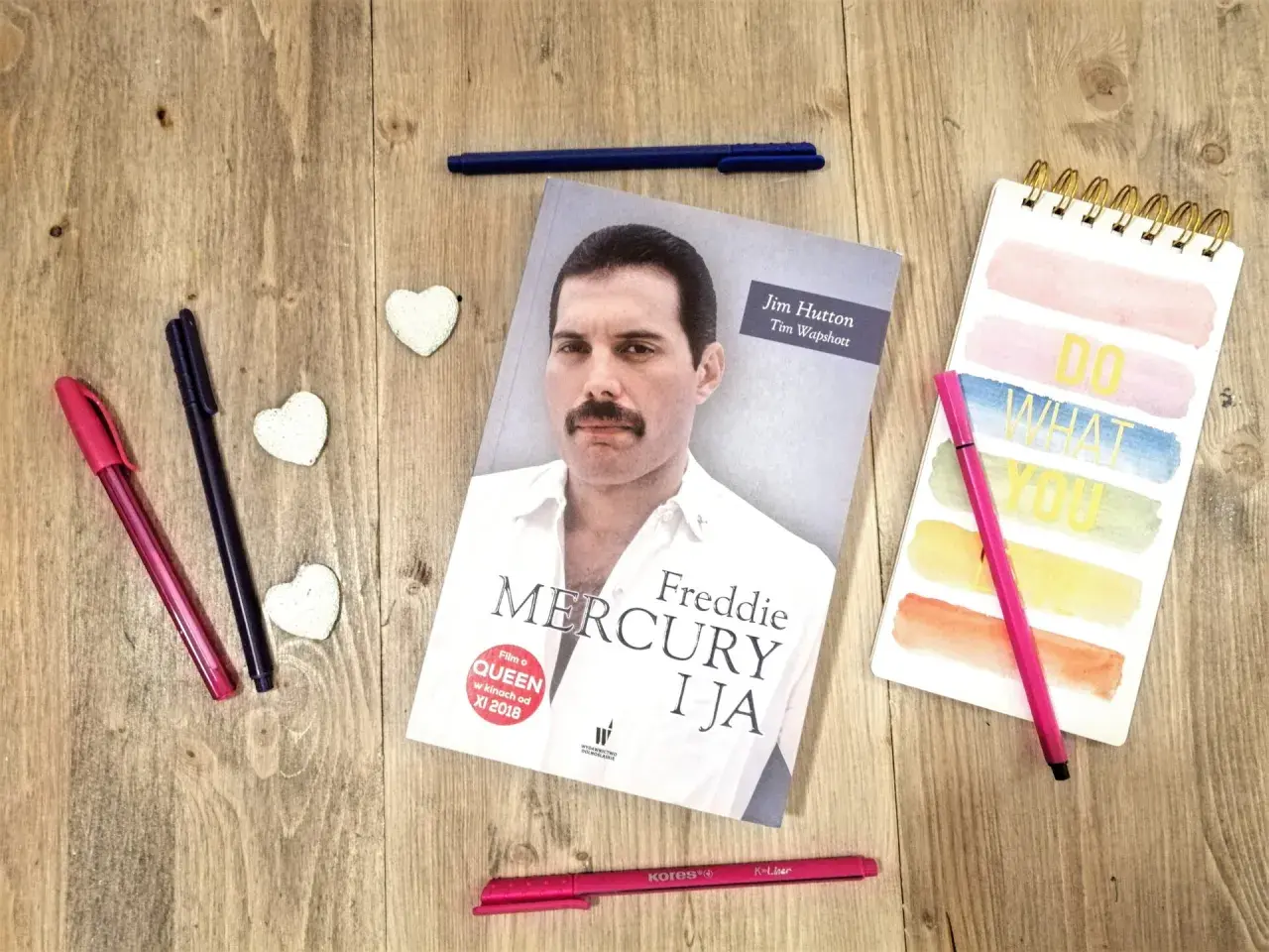 Książka "Freddie Mercury i ja" leży obok kolorowych pisaków i notatnika.