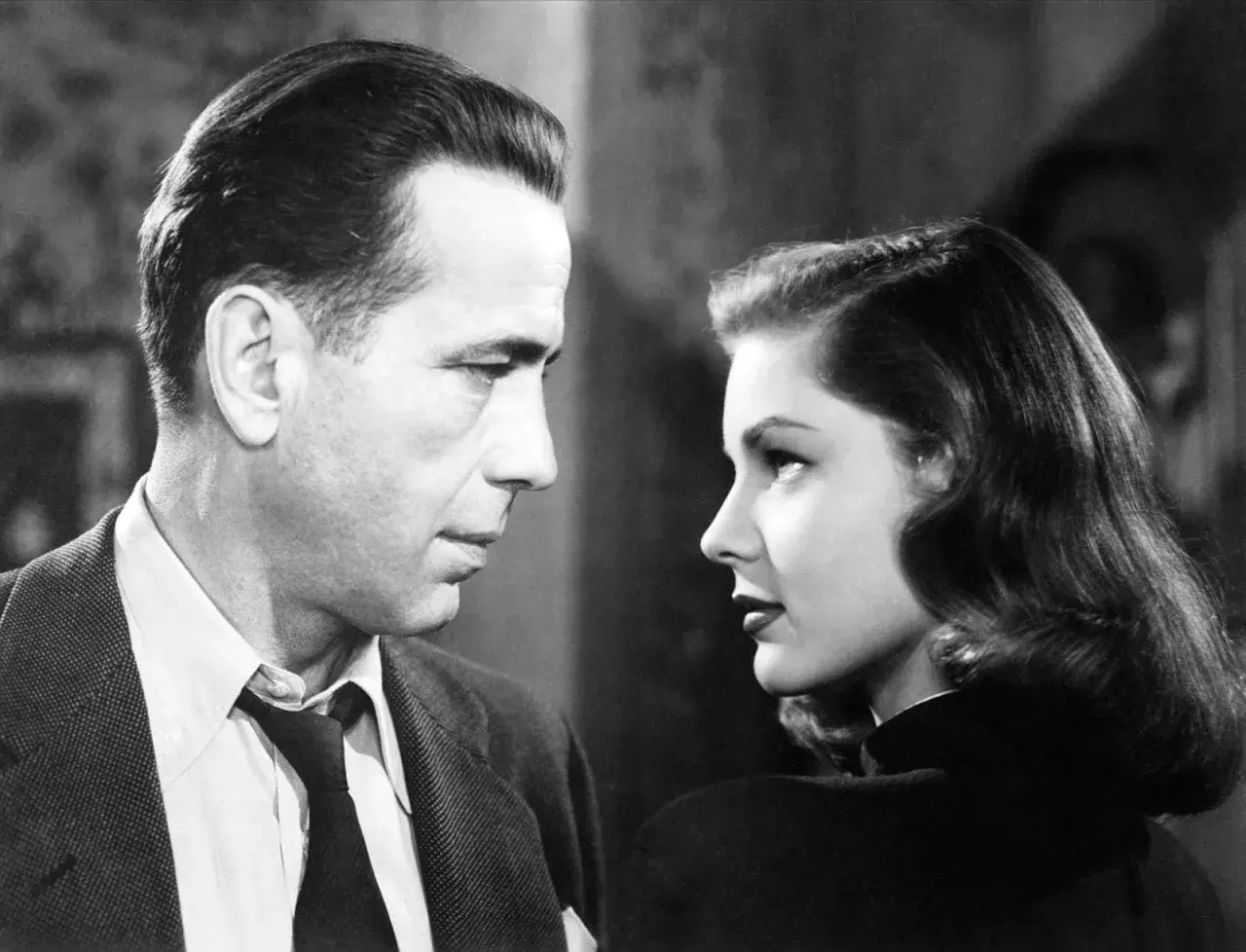 Para z filmu noir patrzy na siebie w zbliżeniu. Mężczyzna w garniturze, kobieta w czarnej sukni.