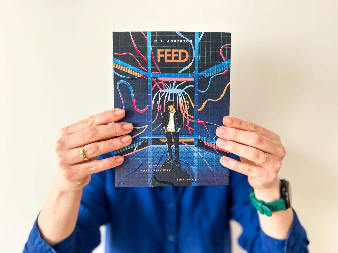 Okładka książki "Feed" M.T. Andersona, przedstawiająca chłopaka w futurystycznym otoczeniu, sugeruje mroczną dystopię.