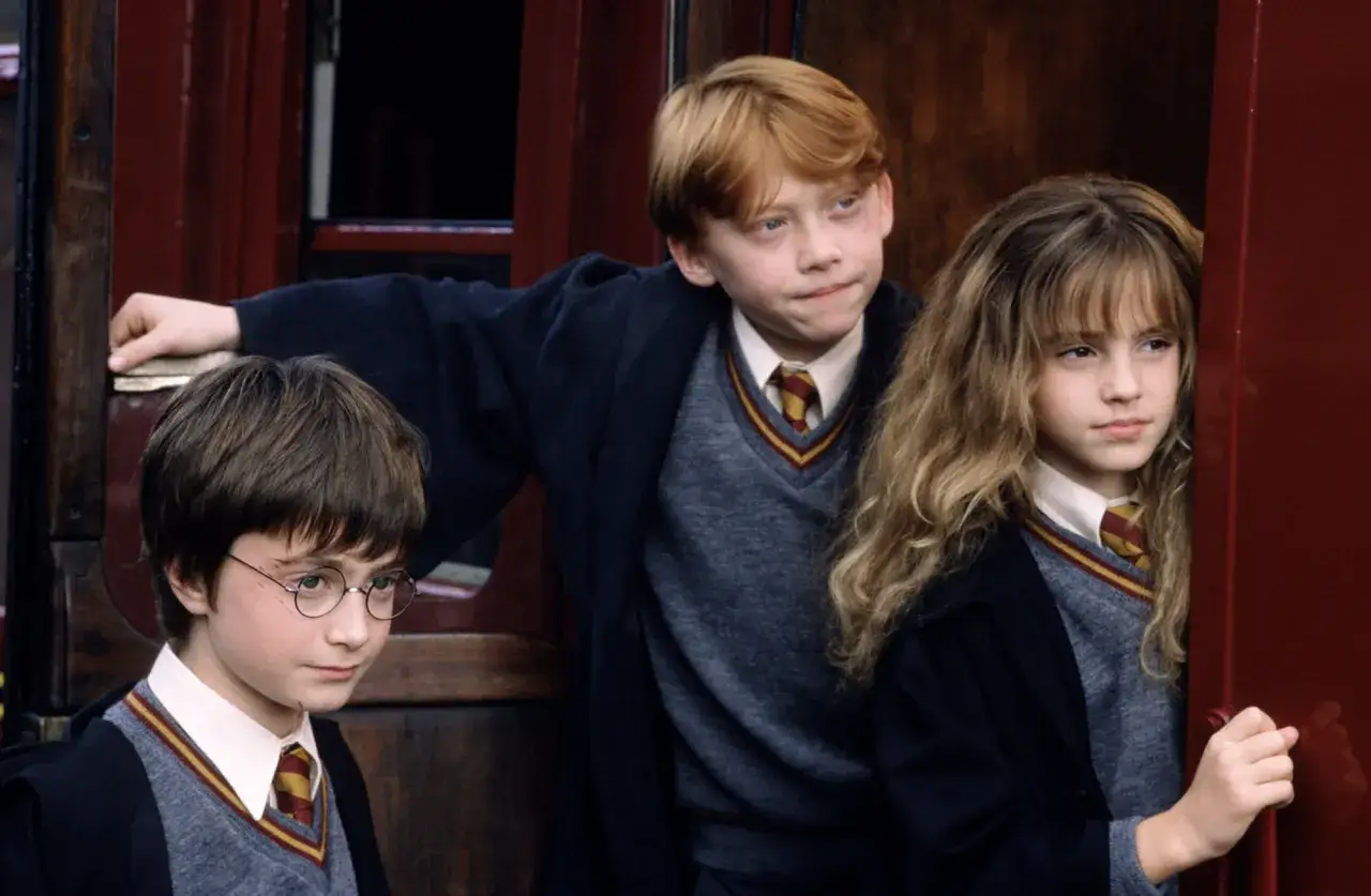 Harry, Ron i Hermiona, znane harry potter postacie, stoją przy drzwiach pociągu.