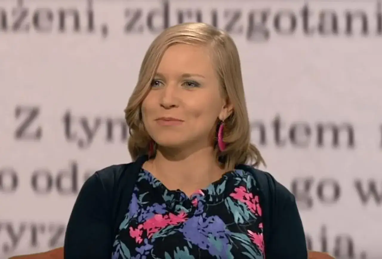 Dorota Masłowska, znana z wykształcenia i twórczości, w kwiecistej bluzce i z różowymi kolczykami.