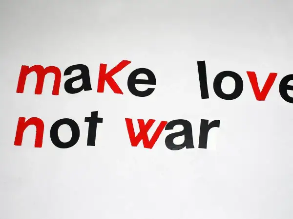 Napis "make love not war" w stylu pacyfista. Czerwone litery podkreślają przesłanie pokoju.