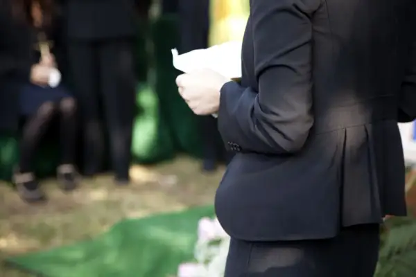 Kobieta w czerni trzyma kartkę, być może czyta panegiryk. Co to jest? To mowa pochwalna, często wygłaszana na pogrzebie.